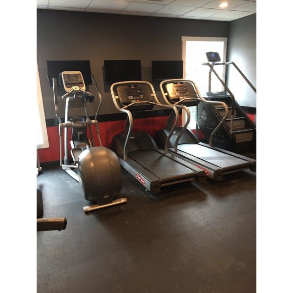 A gym room with treadmills, ellipticals, and weights offering both new and remanufactured gym equipment.