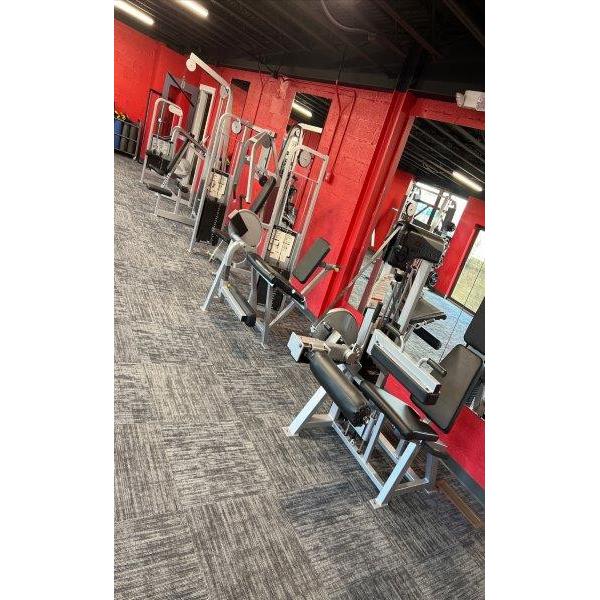 A gym with a lot of new and remanufactured equipment and red walls.