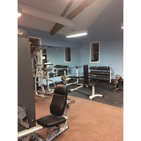 A gym equipped with new weight machines and remanufactured gym equipment, complete with mirrors.