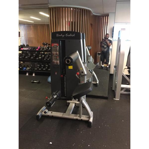 A person standing in front of a new gym machine at the gym.