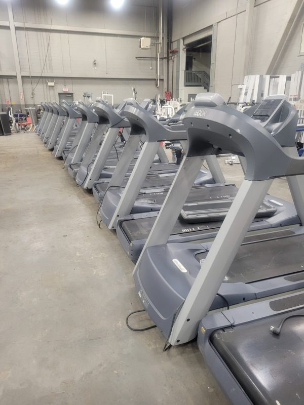 A row of Precor TRM954i Treadmills in a warehouse.