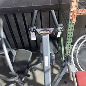 A rowing machine alongside other new and remanufactured gym equipment in a garage, including the Abs Coasters Elite - As Is Functional.