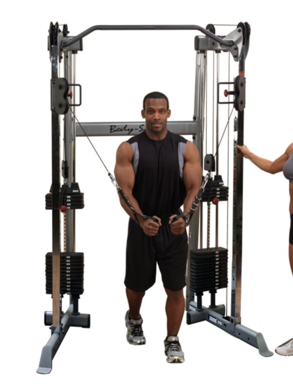 A man and woman standing next to a Body-Solid Functional Trainer 210- New.