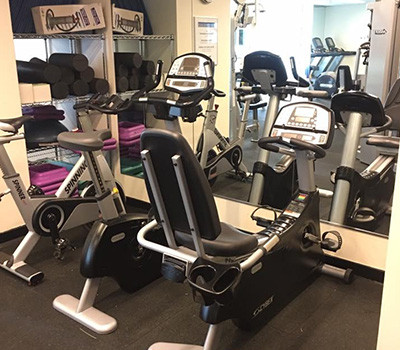 A gym room equipped with exercise bikes and mirrors, offering both new and remanufactured gym equipment.