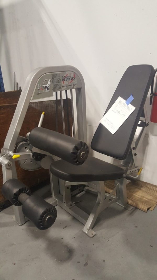 New Nautilus Nitro Seated Leg Curl (Cleaned & Serviced) with a pair of dumbbells on it.