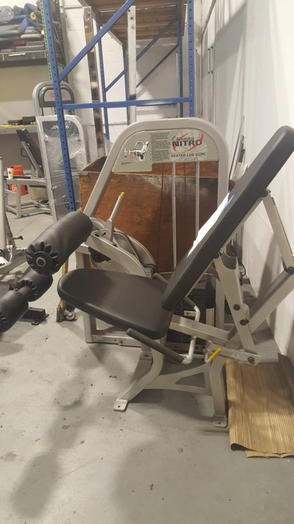 A new Nautilus Nitro Seated Leg Curl (Cleaned & Serviced) is sitting in a warehouse.