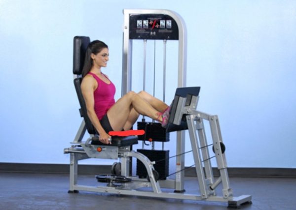 A woman is sitting on a Muscle D Fitness Leg Press/Calf Raise COMBO MACHINE.