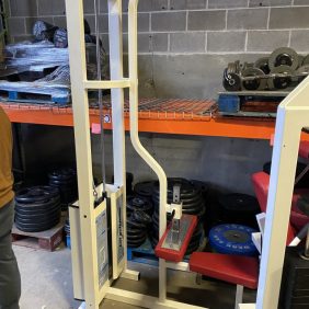 A man standing next to a Reebok Lat Pulldown - As Is Functional in a warehouse.