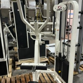 A Cybex VR2 Lat Pulldown weight machine, placed indoors on a wooden pallet, features adjustable weights and a padded seat for functional workouts, surrounded by other gym equipment.