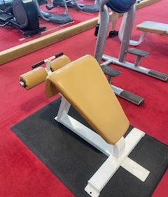 The Icarian Package - Serviced features an incline bench with padded support and a sturdy metal frame, ideally situated on the vibrant red floor of our fully serviced gym.