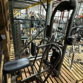 A Matrix Row - As Is Functional machine sits on a wooden pallet in the storage area, seamlessly blending with other gym equipment.