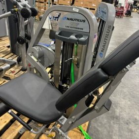 The Nautilus Nitro Leg Extension - As Is Functional machine stands prominently on the warehouse floor, surrounded by pallets and boxes, ready to deliver a functional workout experience.