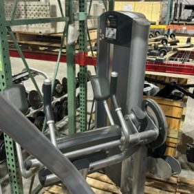 A wooden pallet stacked with functional fitness equipment sits in a storage area, surrounded by shelving and other Life Fitness machinery such as the Signature Abdominal Crunch - As Is Functional.