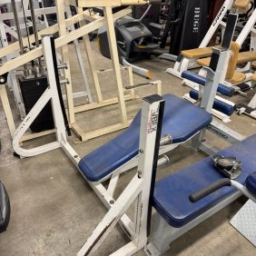 The gym floor is cluttered with various workout equipment, including a Cybex seated calf raise machine, with weights scattered around next to a Cybex Olympic Decline Bench costing $350.