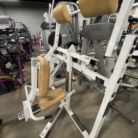 A gym offers diverse exercise machines, including a remanufactured Precor Stretch Machine with padded seats, set on a concrete floor.