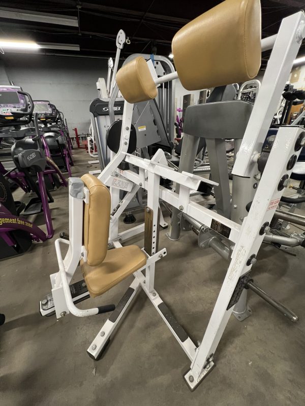 A gym offers diverse exercise machines, including a remanufactured Precor Stretch Machine with padded seats, set on a concrete floor.