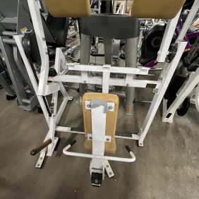 Reimagined with a sleek Precor design, the remanufactured gym leg press machine boasts tan cushions and a robust metal frame, resting elegantly on polished concrete.