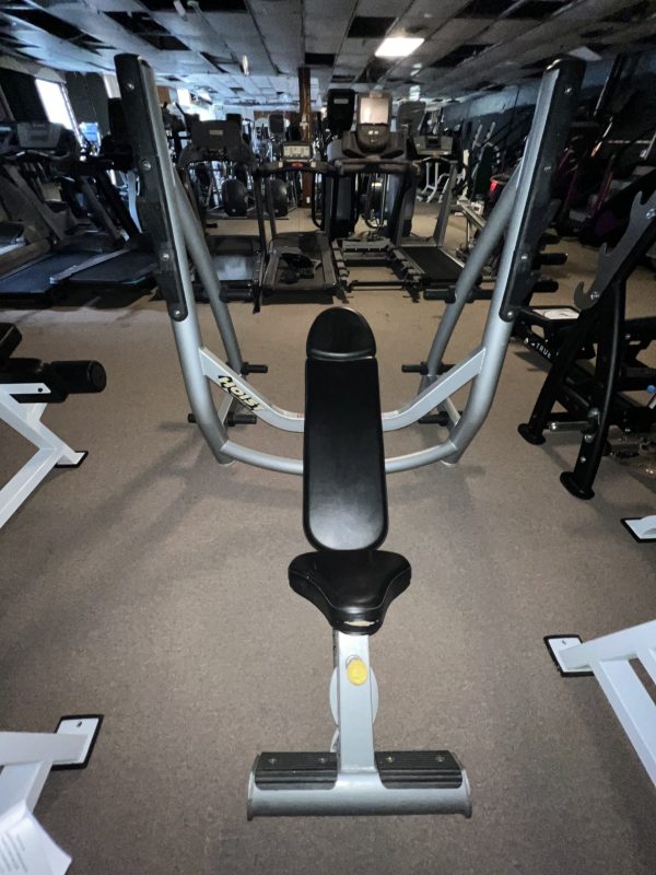 A gym bench is centered in a fitness facility filled with various exercise equipment, including a remanufactured Precor Stretch Machine - Remanufactured.