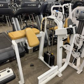 In a gym, a yellow and white weight machine labeled "Nautilus" with the number "13" stands among treadmills. Nearby, an Icarian Glute Isolator offers targeted workouts for $995.