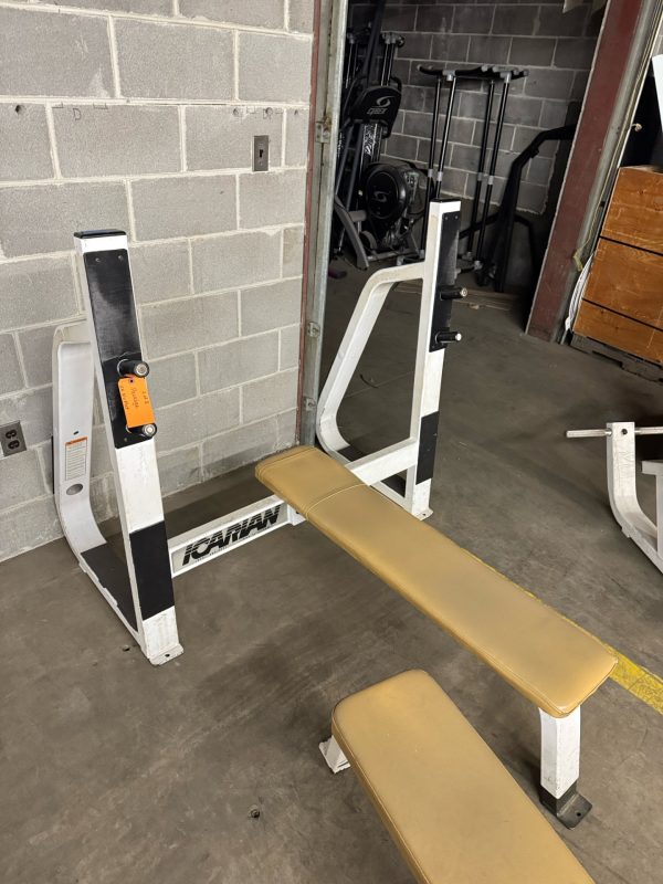 The True XFW 8200 Olympic 3 Way - New complements the beige padding and white frame of the old bench press, standing out against the gym's bare gray walls.