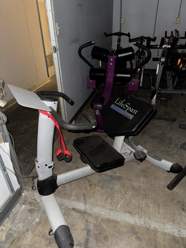 The Life Fitness Signature Ab Crunch, priced at $1995, features black and purple padding and comes with handles and a step platform. Ideal for indoor workouts on a concrete floor, it is perfect for an effective ab crunch routine.