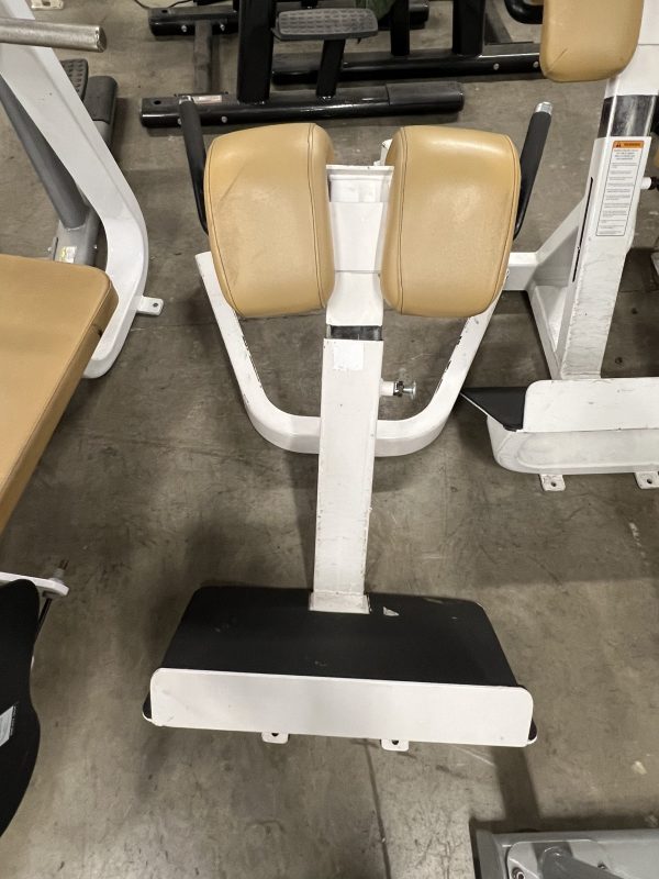 A remanufactured Precor Stretch Machine with light brown padding sits elegantly on the concrete floor, showcasing its sleek design.