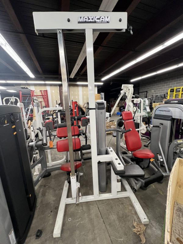 A gym features various weight machines, including a remanufactured Maxicam seated row with red padded seats and metal frames, along with a remanufactured Precor Stretch Machine.