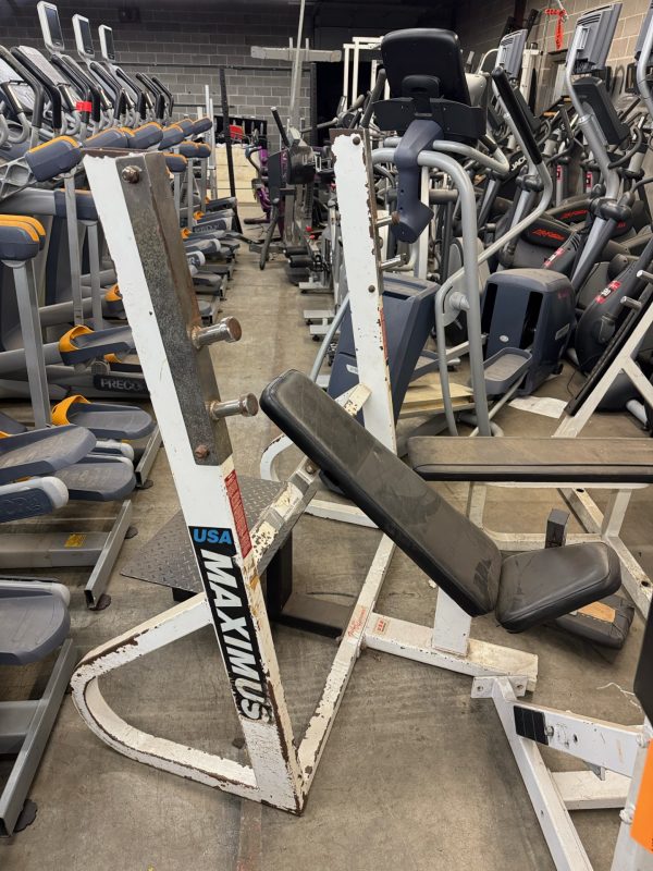 The Maximus Incline Bench Press - As Is Functional, despite its rusted frame, continues to operate among other gym equipment in storage.