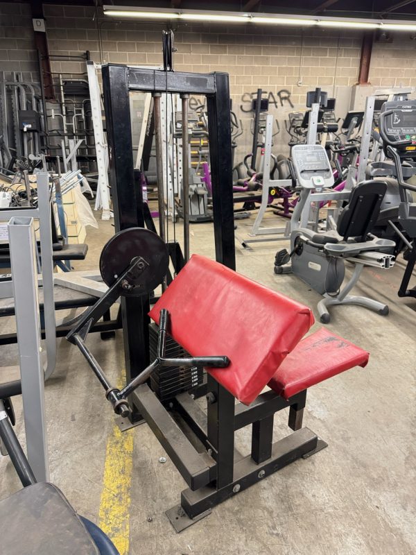 A cluttered room with gym gear, including a Life Fitness Signature Ab Crunch machine in black for $1995, stands amongst various exercise machines and graffiti-covered walls.