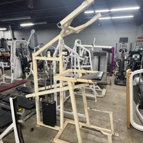 The True XFW 8200 Olympic 3 Way - New gym machine features a sturdy metal frame and padded seat, blending seamlessly with the various workout equipment in this Olympic-inspired gym.