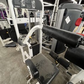 A remanufactured Precor Stretch Machine sits in a workout area with concrete flooring, surrounded by other exercise equipment, including a gym leg press machine.